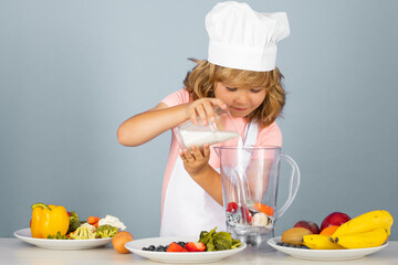 Child chef isolated on blue make milk shake smoothie . Funny little kid chef cook wearing uniform cook cap and apron cooked food in the kitchen.