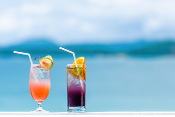 Two cocktails in luxury resort in sunny summer day. Mocktail drinks with straw in tropical luxurious hotel. Travel, vacations, holidays, tourism concept. Turquoise sea blurred background. Copy space.