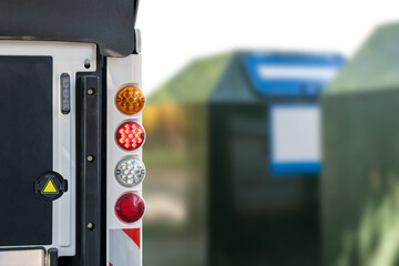 Teil von einem Reinigungsfahrzeug mit grünen Containern im Hintergrund