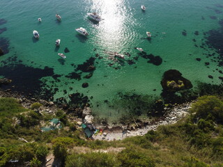 Aerial panoramic view of seascape with crystal clear azure sea and rocky shores. Yachts in a beautiful lagoon on backdrop of rocks. The concept of an ideal destination for summer travel and vacation.