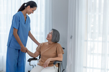 Obraz premium Young nurse taking care elderly disabled woman sitting in a wheelchair with copyspace.