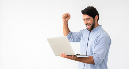 Happy excited Caucasian man holding laptop and raising his arm up to celebrate success or achievement on white background