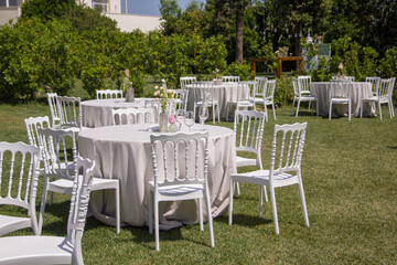 Image of a garden with white tables and chairs set up for a banquet