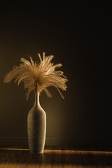 Aesthetic dried pampas grass / fluffy reed in stylish clay pot vase. Shadows on the wall. Silhouette in sun light. Minimal boho interior decoration