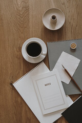 Obraz na płótnie Canvas Aesthetic minimalist concept. Paper sheet notebook, cup of coffee, album, stationery on wooden table background. Flat lay, top view