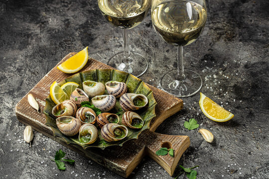 Baked snails with butter and spice on dark background. Snails baked with sauce wine glass, Bourgogne Escargot Snails. gourmet food. concept of french cuisine, top view