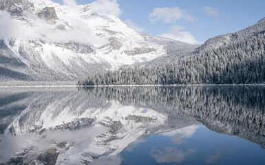 Still alpine lake reflecting its winter surroundings like a mirror, Yoho N. Park, Canada