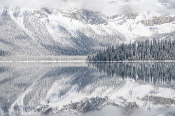Still alpine lake reflecting its winter surroundings like a mirror, narrow, Yoho N. Park, Canada
