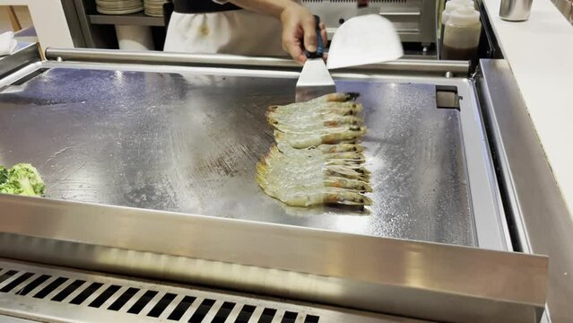 Zubereitung von frischen Garnelen, Meeresfr&uuml;chten auf einer hei&szlig;en Kochplatte.