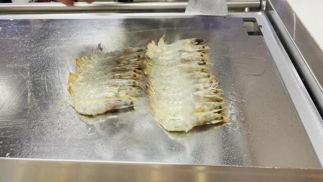 Zubereitung von frischen Garnelen, Meeresfr&uuml;chten auf einer hei&szlig;en Kochplatte.