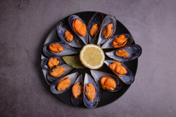 Ration of cooked mussels from the Galician estuary garnished with lemon and bay leaf.
