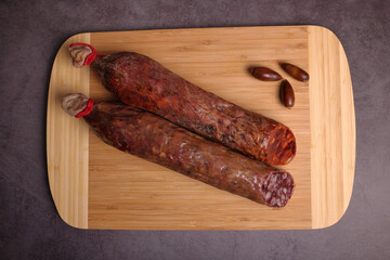 Iberian sausage and Iberian chorizo on cutting board and dark gray table.