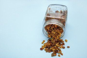 raisins in an overturned jar on a blue background with copy space