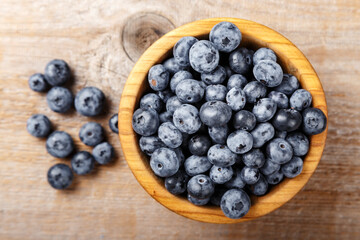 Freshly picked blueberries in a wooden bowl. Healthy food and nutrition concept.