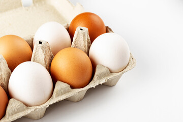 A tray of  fresh hens eggs on white background. Eco-friendly egg production. Baking ingredients. Organic chicken eggs - fresh from producer. Top view.