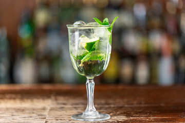 Martini royale alcoholic cocktail with white vermouth, prosecco, lime, mint and ice on the bar.