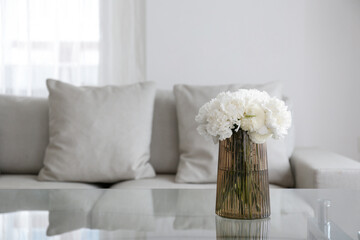 Empty apartment with minimal loft style interior, glass vase with bouquet of peonies on foreground...