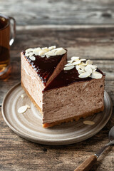 Two chocolate cheesecake slices with almond petals topping in composition with a cup of tea on wooden background
