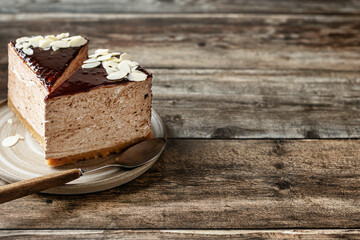 Two chocolate cheesecake slices with almond petals topping on wooden background. Copy space