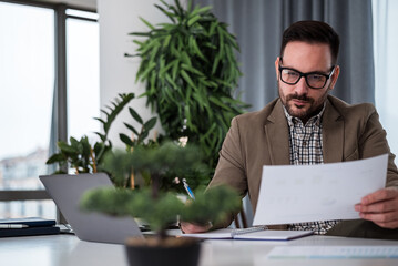 Serious executive analyzing documents while planning business strategy at office