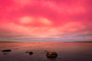 Fototapeta na wymiar Dramatic vibrant sunset seascape over the Martha's Vineyard in Massachusetts. The swirling pink clouds over the rocky bay on Cape Cod and Island.