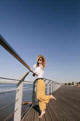 Woman happy in a summer hat under the sun. Girl enjoying sunny day looking up at sky smiling cheerful.