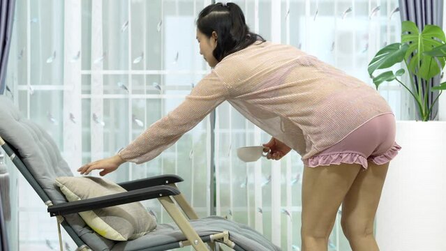 Footage 4K, Asian pregnant woman sitting on the sofa drinking tea around the house window