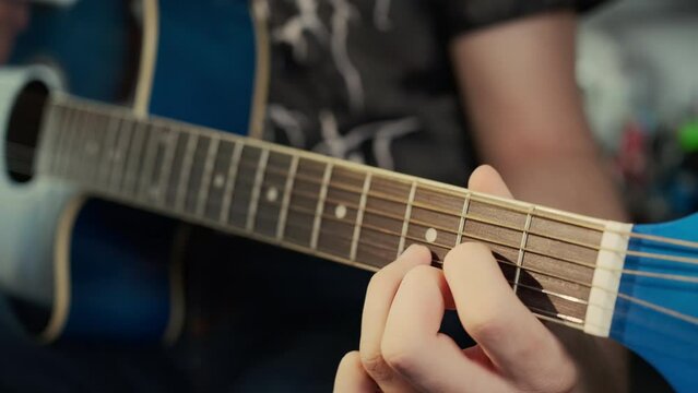 Musician man at home playing a six-string guitar. Close-up, soft focus. Fingers on strings, live video
