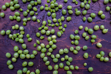 Fresh peeled green pease on a brown wooden table with copy space. Still life of green peas in pods with pea shoots on wooden table