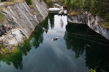 Fototapeta na wymiar A man jumping from a bungee over a canyon in the Ruskeala mountain park in Karelia, Russia