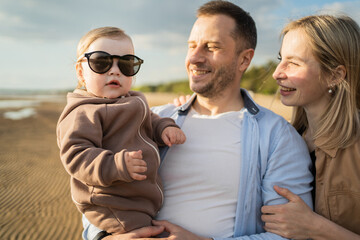 Obraz premium Family happy parents baby girl smiling walking playing on the beach