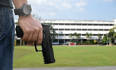 9mm pistol gun holding in right hands of shooter in front of the grass court with blurred office...