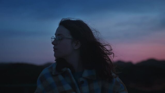 Closeup cinematic soft portrait of pretty millennial teenage female with brunette curly windy hair wearing casual cosy warm plaid shirt, stylish eyeglasses, dreaming and thinking outdoors in Porto