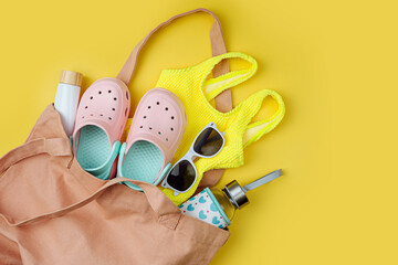 Beach bag with beach accessories for kids. Swimsuit, sunglasses, beach slippers and sunscreen for...