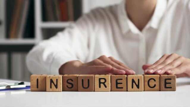 a woman moves letters folding the word insurance, the text insurance is laid out on a white table, an asian girl an insurance agent folds the text life insurance
