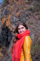 Portrait of a girl with long hair in a yellow jacket and an orange scarf on a sunny autumn day