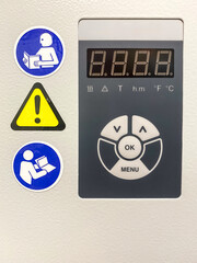 A control panel of a modern laboratory water bath with safety signs. Stickers with pictograms indicates that a user should refer to instruction manual and remain cautious.