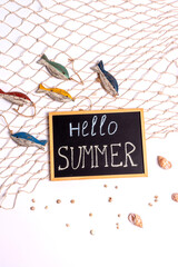 Marine still life: a board with the inscription "nello summer" on a sea net, wooden fish and seashells on a white background