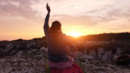 Woman practicing yoga outdoors in sunset sunrise time.