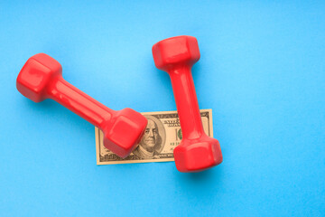 two red dumbbells on a blue background and one hundred dollars