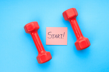 between two red dumbbells on a blue background is a sheet of paper with the inscription start
