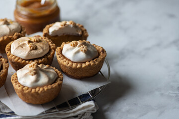 Lemon curd tartlets with whipped meringue on a wire rack. Copy space and close up.