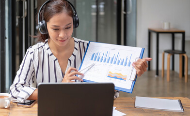 Happy asian woman young wearing headset, communicating with client via video computer call.