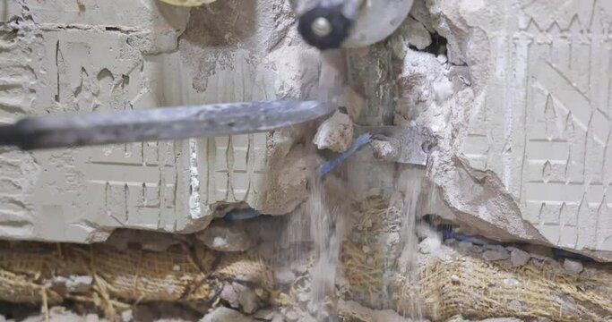 Plumber using a jackhammer to drill into wall, professional worker replaces old water pipes, slow motion