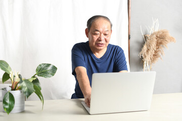 ノートパソコンを操作する高齢者男性