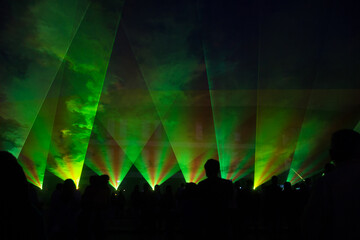 Laser lights and people silhouettes at city square. Celebrating city anniversary.