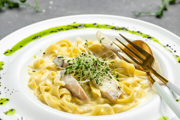 Fettuccine alfredo in a creamy sauce with chicken, parmesan on white plate. Pasta alfredo with chicken. Italian cuisine. banner, menu, recipe place for text, top view