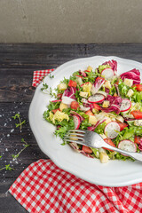 Fresh salad with mixed greens radish cheese and tomato in a plate on wooden background. Italian Mediterranean or Greek cuisine. Vegetarian vegan food.