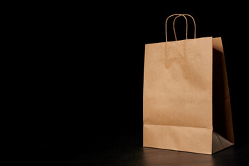 Brown paper bag with carrying handles insulated on a black background. The layout of the packaging...