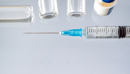 One glass vial of liquid, a vaccine, and a medical syringe close-up on a blue background. concept of vaccination against coronavirus . Banner, copy space.